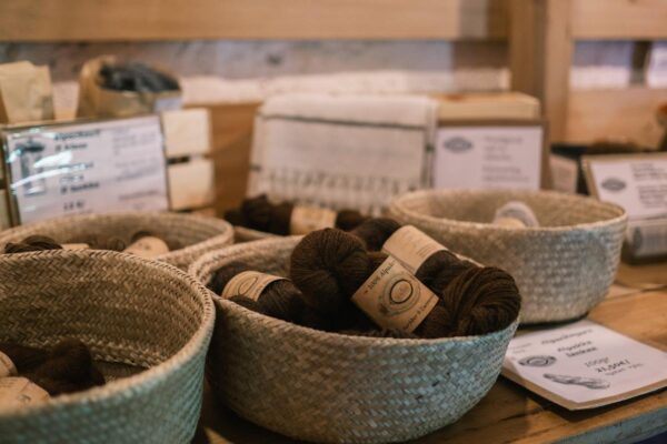 A display of yarn in baskets on a wooden table.